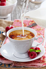 Cup of tea with milk pouring over