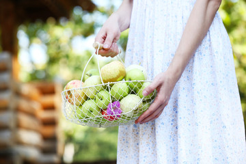 Girl holding basket of apples outdoors