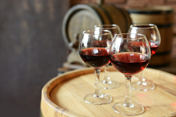 Glasses of wine in cellar with old barrels