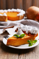 Piece of homemade pumpkin pie on plate on wooden background