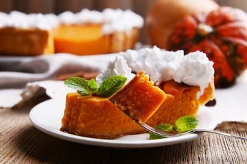 Piece of homemade pumpkin pie on plate on wooden background