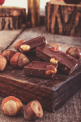 cubes of chocolate with hazelnuts or nuts around  on  wooden pie