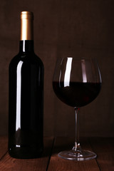 Red wine glass and bottle of wine on dark background