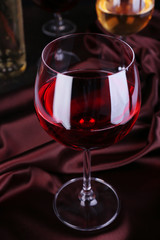 Red wine glass with bottles and glasses of wine close-up