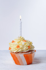 Delicious birthday cupcake on table on white background