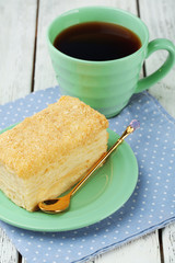 Napoleon cake on plate and cup of tea on table close-up