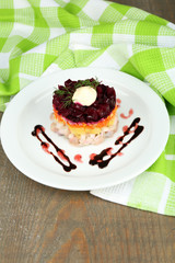 Russian herring salad on plate on wooden table background