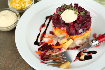 Russian herring salad on plate on wooden table background