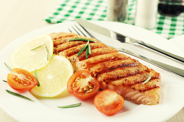 Grilled salmon and vegetables on plate on wooden background