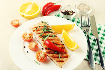 Grilled salmon and vegetables on plate on wooden background