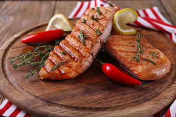 Grilled salmon on cutting board on wooden background