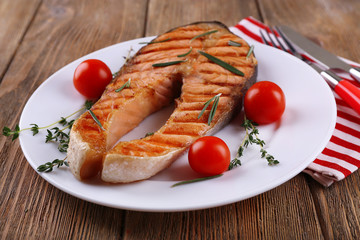 Grilled salmon and vegetables on plate on wooden background