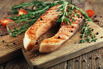 Grilled salmon on cutting board on wooden background
