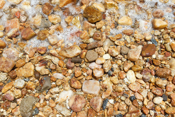 Background colorful wet stones on beach with water