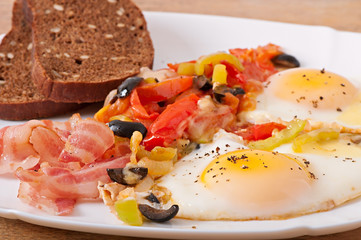 Breakfast - fried eggs with bacon, tomatoes, olives and cheese