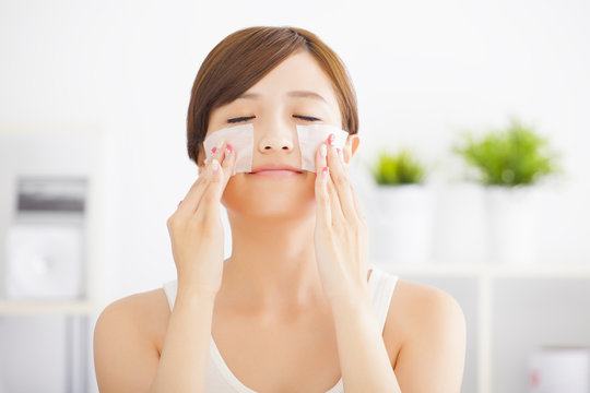 Beautiful  young woman cleaning her face with cotton