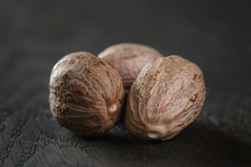 whole nutmegs in olive bowl on oak table