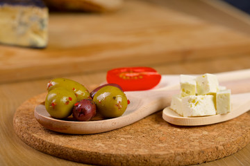 Olives and tomato on a wooden spoons