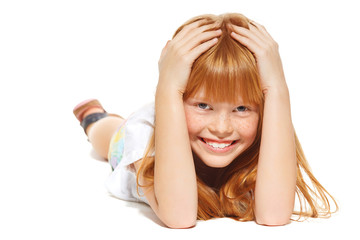 A cheerful little girl with red hair is lying; isolated