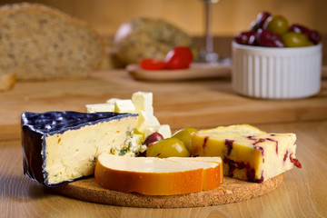 Various cheese and olives on a wooden board