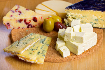 Various cheese and olives on a wooden board