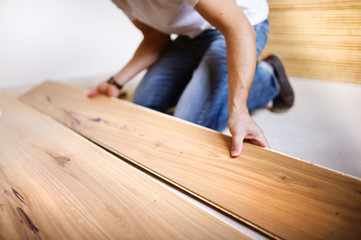 Handyman installing wooden floor - obrazy, fototapety, plakaty