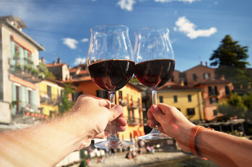 Two wineglasses in the hands. Varenna town at the lake Como, Ita