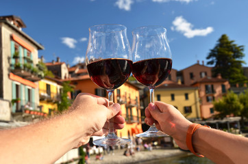 Two wineglasses in the hands. Varenna town at the lake Como, Ita