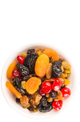 Mix variety of dried fruit in white bowl over white background