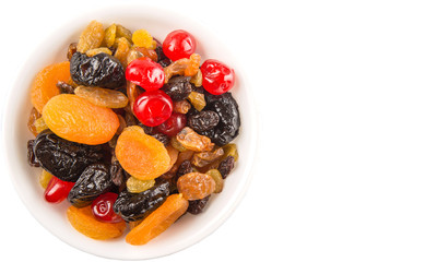 Mix variety of dried fruit in white bowl over white background