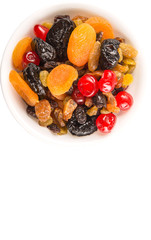 Mix variety of dried fruit in white bowl over white background