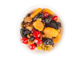 Mix variety of dried fruit in white bowl over white background