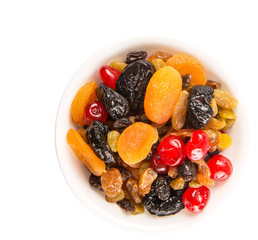 Mix variety of dried fruit in white bowl over white background
