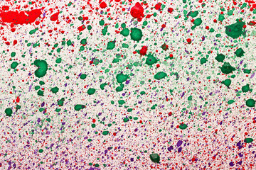 Multicolored drops of paint on the white paper