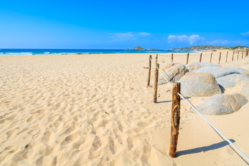 Fototapeta na wymiar Fence on beautiful golden sand Chia beach, Sardinia island