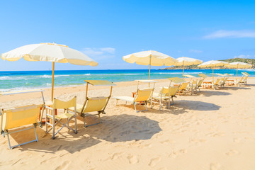 Sunbeds with umbrellas on Sa Colonia beach, Sardinia island