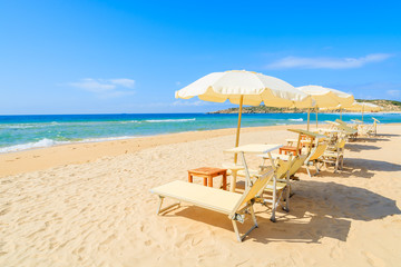 Sunbeds with umbrellas on Sa Colonia beach, Sardinia island