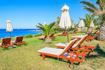 Sunbeds with umbrellas in tropical garden, Sardinia island