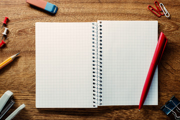 Red pen ready for writing on an open notebook