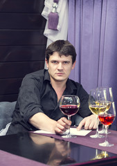 young man tasting wine at a table in a restaurant