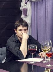 young man tasting wine at a table in a restaurant