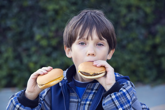 boy outdoors eating a hamburger