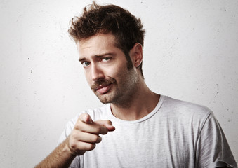 Young mustached man pointing towards the camera