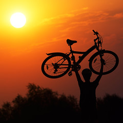 Fototapeta na wymiar Tourist with a bike on the sunset background.
