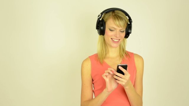 woman listens to music with headphones with phone - studio