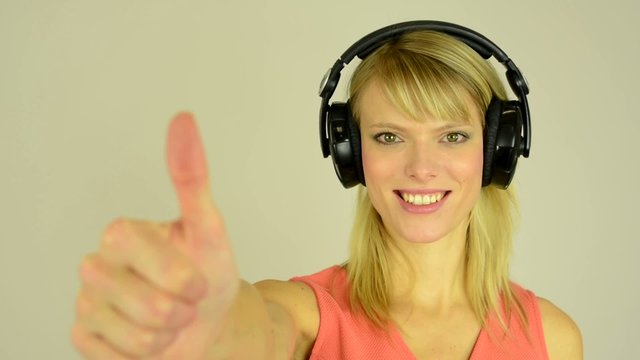 woman listens to music with headphones and shows a thumbs up
