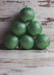 Green christmas balls in a stack over wooden background