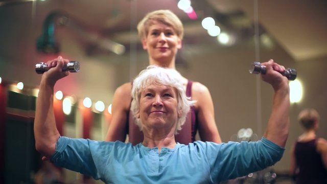 Senior Frau und Trainer mit Hanteln bei Fitness Sport