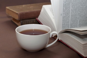 Cup of black tea and some books to read lying on the brown surfa