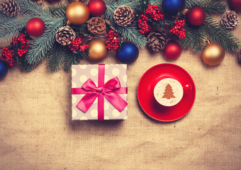 Hot cappuccino with christmas tree shape on a table near pine br